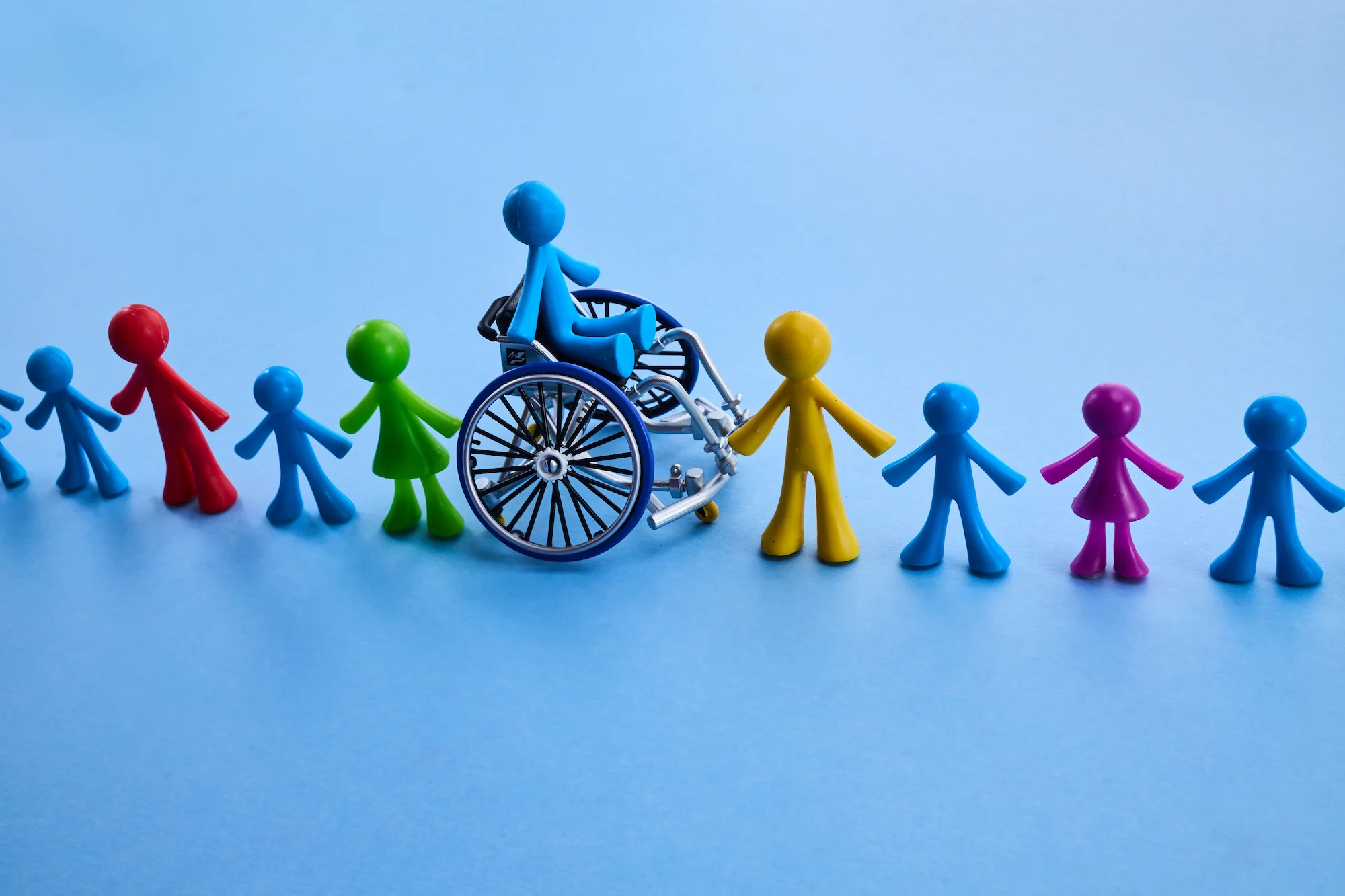 Illustration of a wheelchair user surrounded by people, representing inclusive Specialist Disability Accommodation (SDA), participant support and accessible housing.